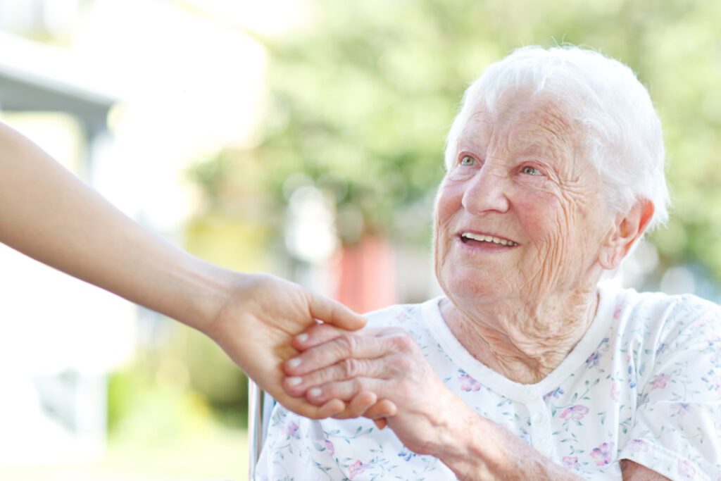 Het vastpakken van een hand van een oudere vrouw - Hospice-info
